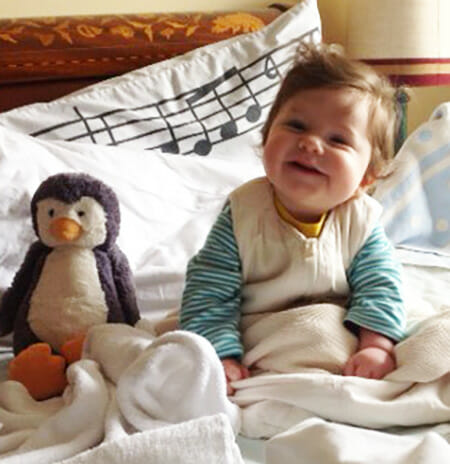 Bea's Fertile Heart Baby on bed with stuffed penguin