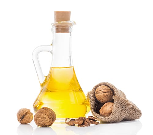 Walnut Oil Walnut Oil in Flask with Walnuts on table around it